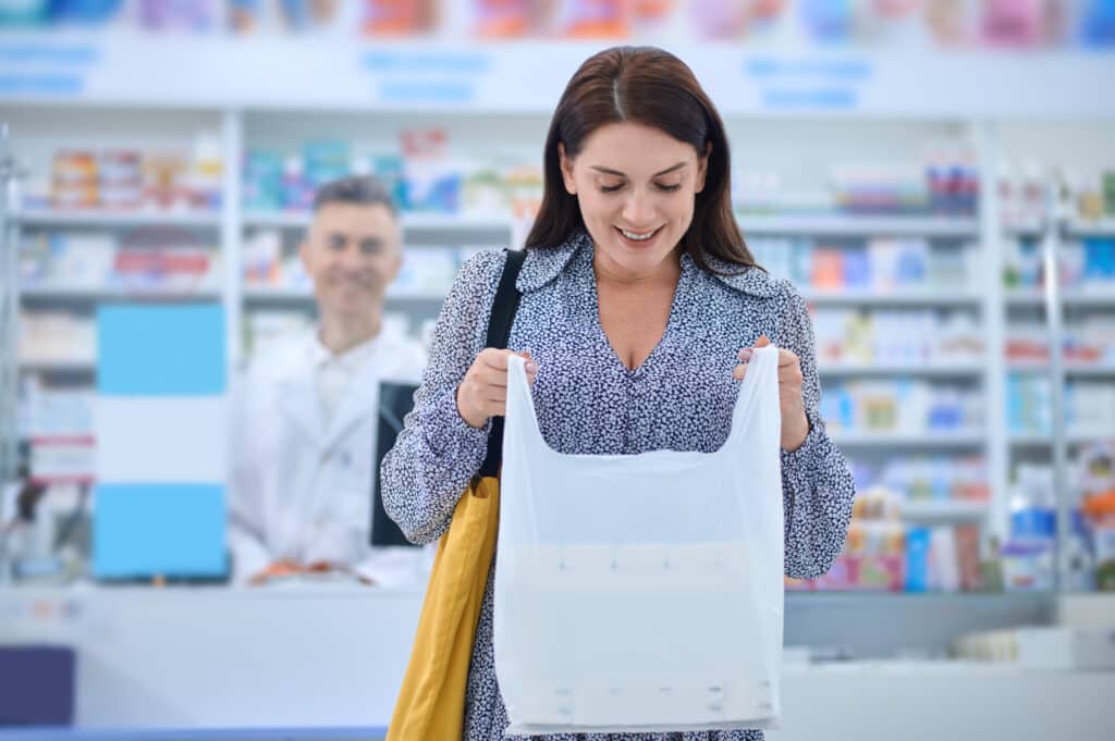 Woman shopping at a pharmacy, holding a bag.