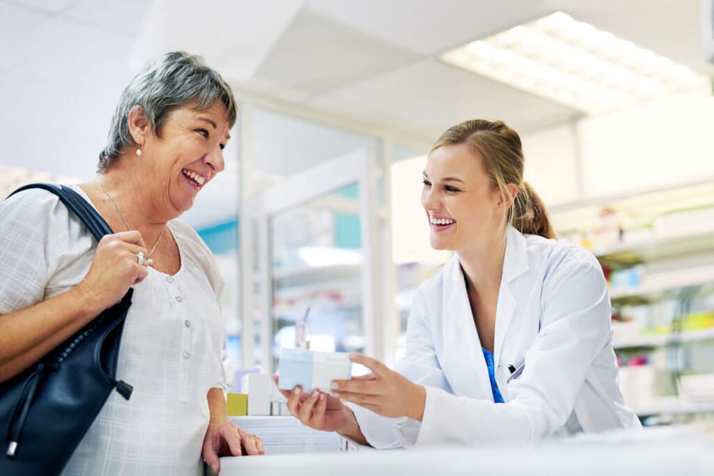 Pharmacist assisting smiling customer in pharmacy.