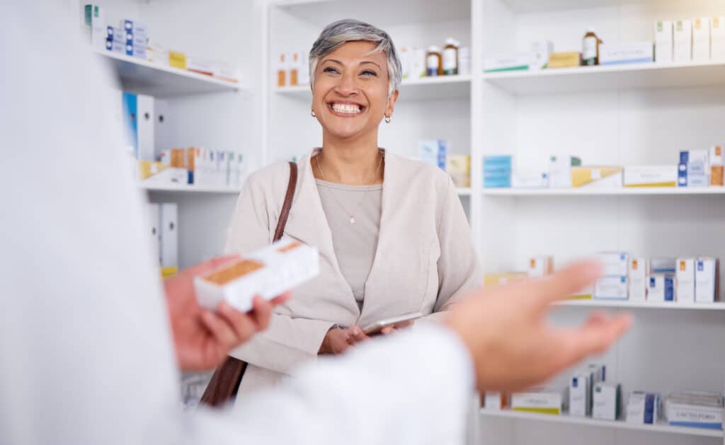 Smiling woman at a pharmacy, receiving medication.