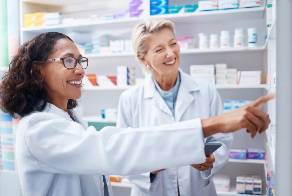 Pharmacists discussing medicine on shelf.