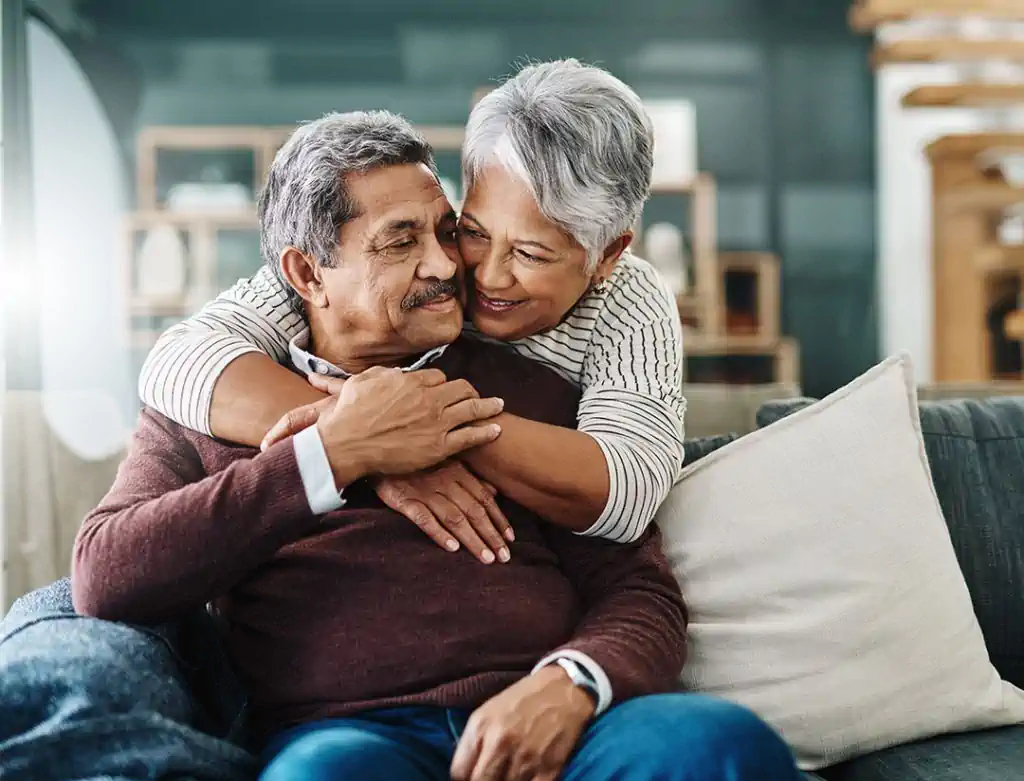 Elderly couple embracing on living room couch