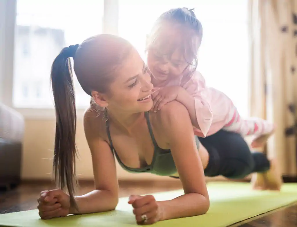 Mother doing plank exercise with child on back