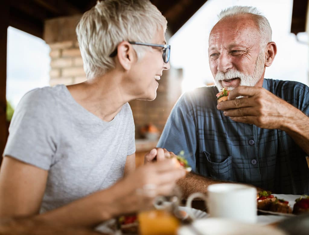 Senior couple laughing while eating breakfast together